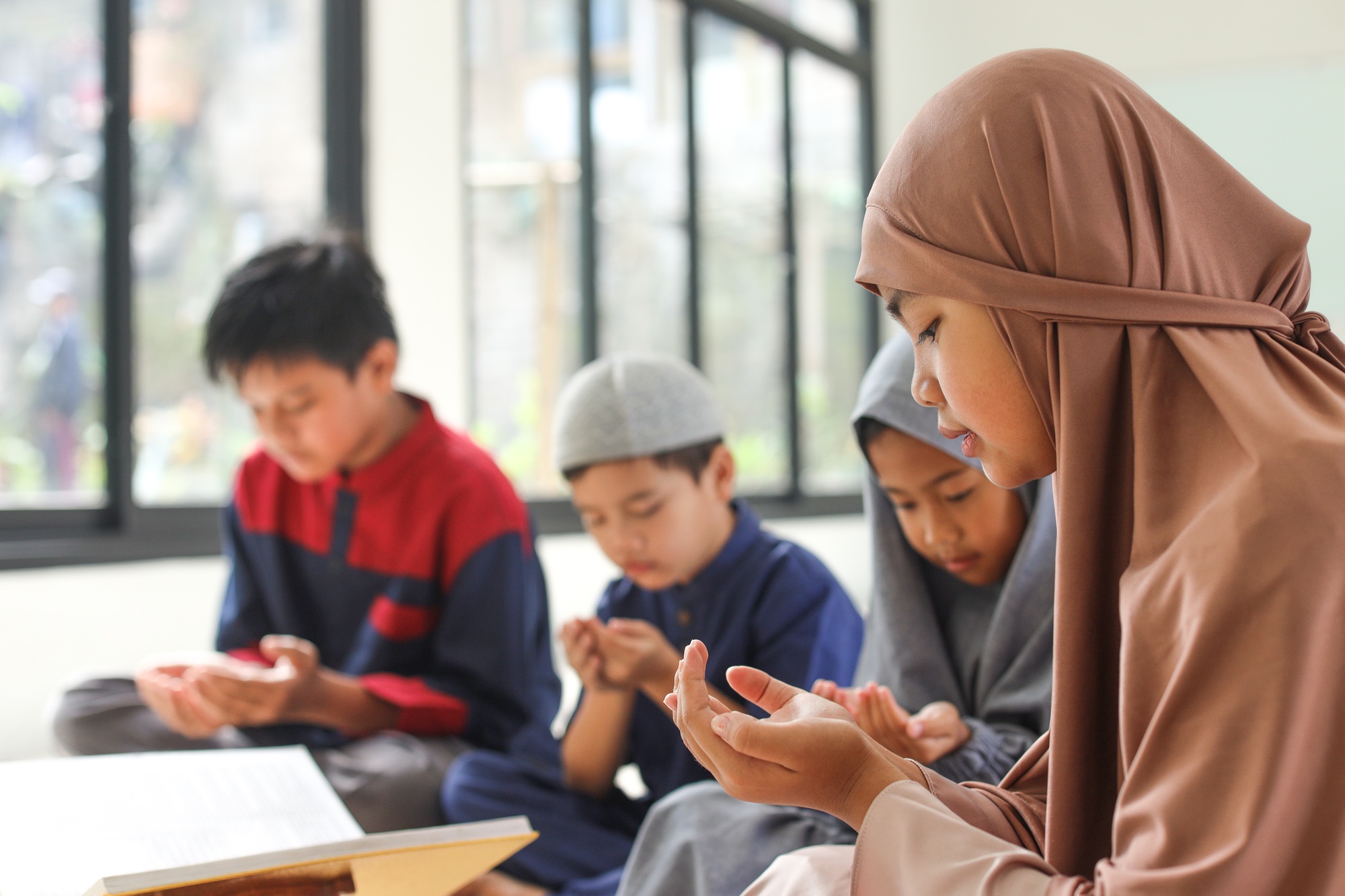 Group of muslim kids praying before reciting Quran